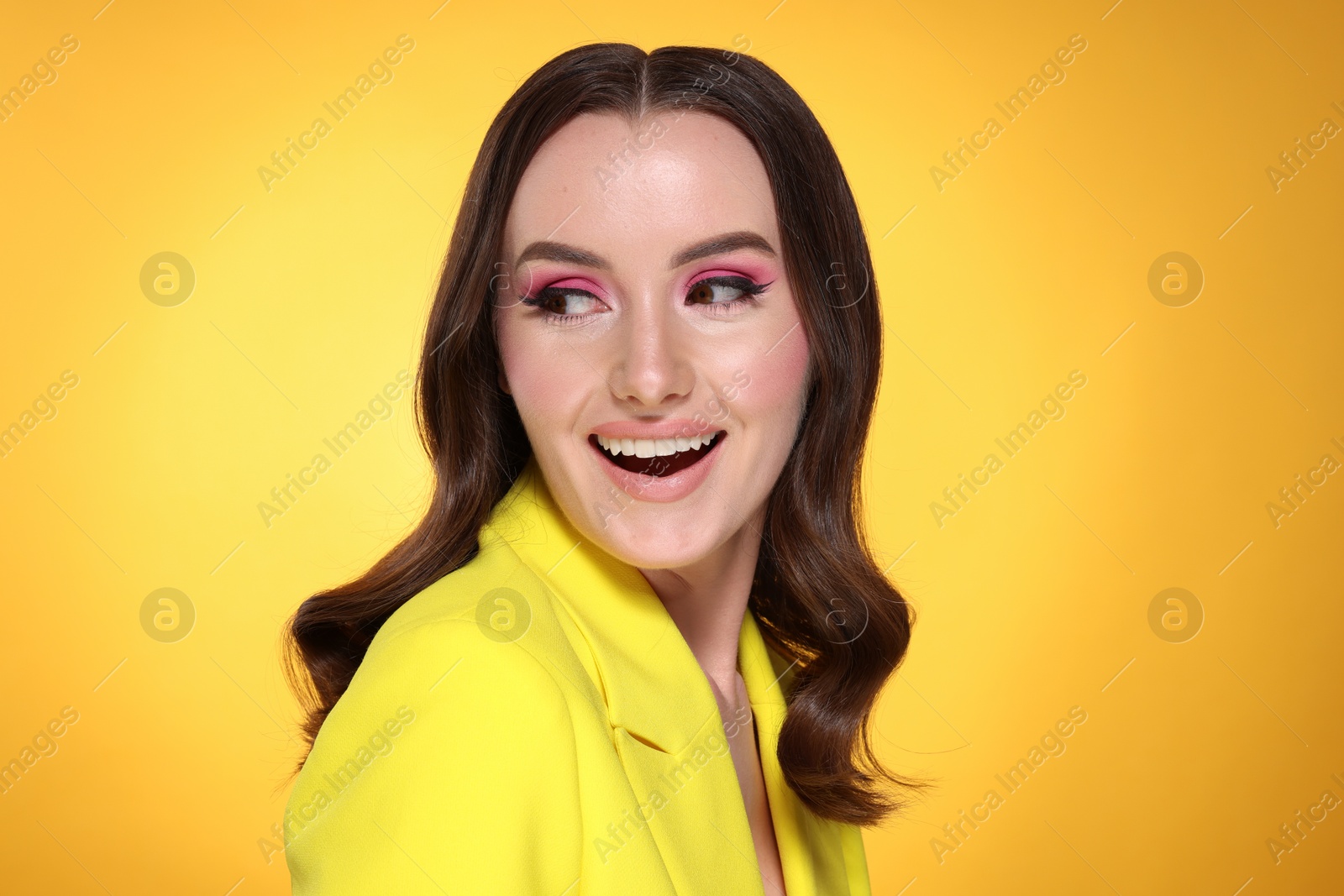 Photo of Portrait of beautiful young woman with stylish makeup and gorgeous hair on yellow background