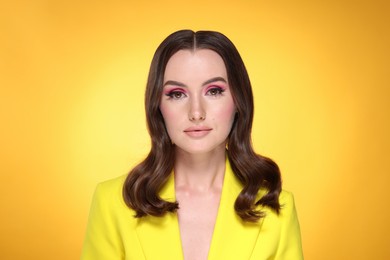 Photo of Portrait of beautiful young woman with stylish makeup and gorgeous hair on yellow background