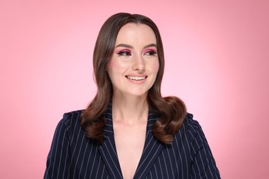 Photo of Portrait of beautiful young woman with stylish makeup and gorgeous hair on pink background