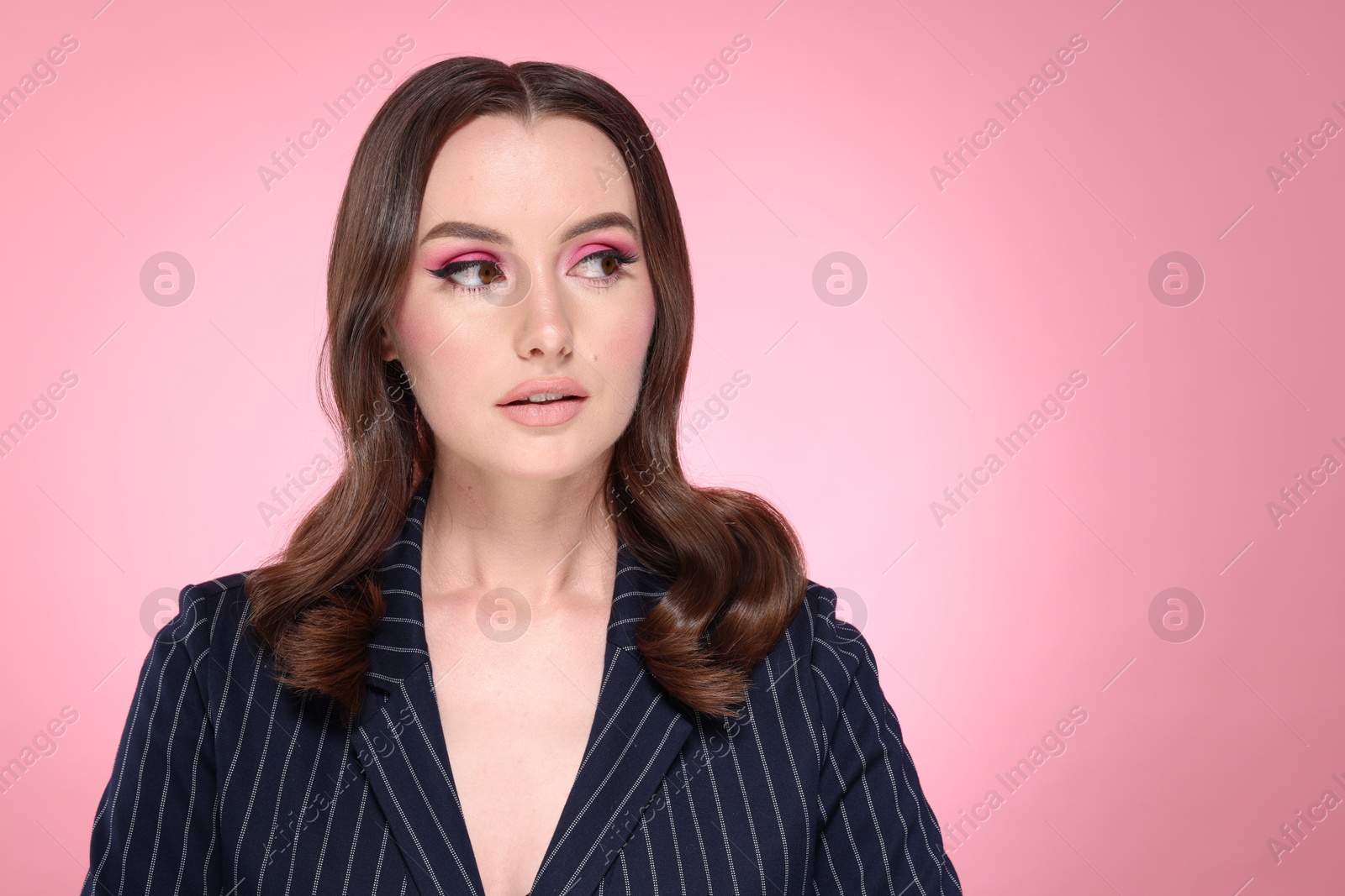 Photo of Portrait of beautiful young woman with stylish makeup and gorgeous hair on pink background. Space for text