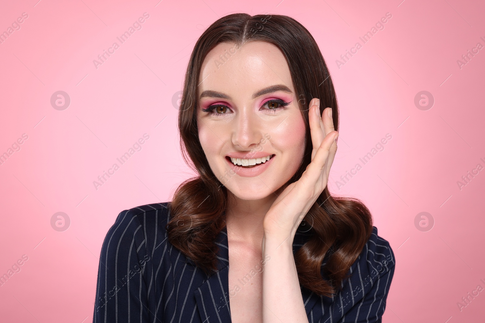 Photo of Portrait of beautiful young woman with stylish makeup and gorgeous hair on pink background