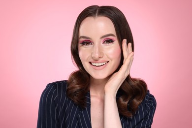 Portrait of beautiful young woman with stylish makeup and gorgeous hair on pink background