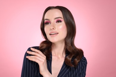 Photo of Portrait of beautiful young woman with stylish makeup and gorgeous hair on pink background