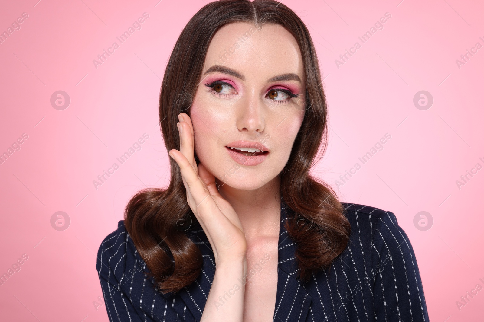 Photo of Portrait of beautiful young woman with stylish makeup and gorgeous hair on pink background