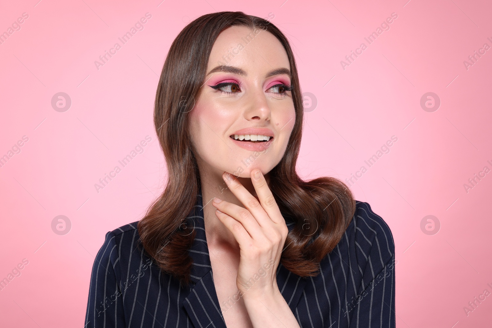 Photo of Portrait of beautiful young woman with stylish makeup and gorgeous hair on pink background