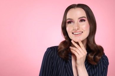 Photo of Portrait of beautiful young woman with stylish makeup and gorgeous hair on pink background. Space for text