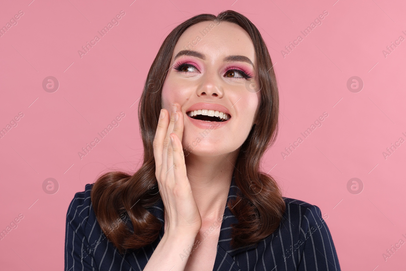 Photo of Portrait of beautiful young woman with stylish makeup and gorgeous hair on pink background