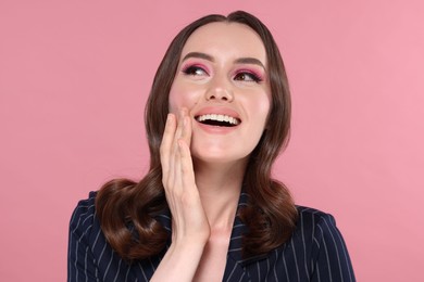 Photo of Portrait of beautiful young woman with stylish makeup and gorgeous hair on pink background