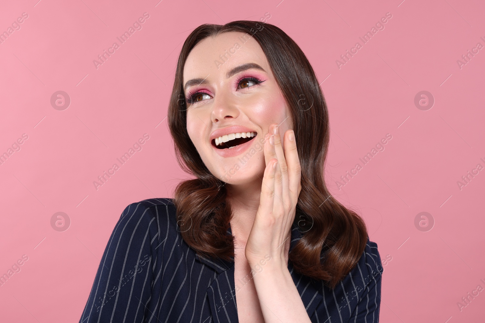 Photo of Portrait of beautiful young woman with stylish makeup and gorgeous hair on pink background