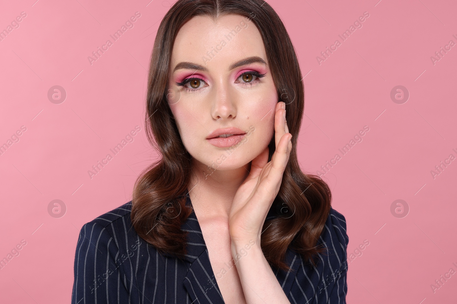 Photo of Portrait of beautiful young woman with stylish makeup and gorgeous hair on pink background