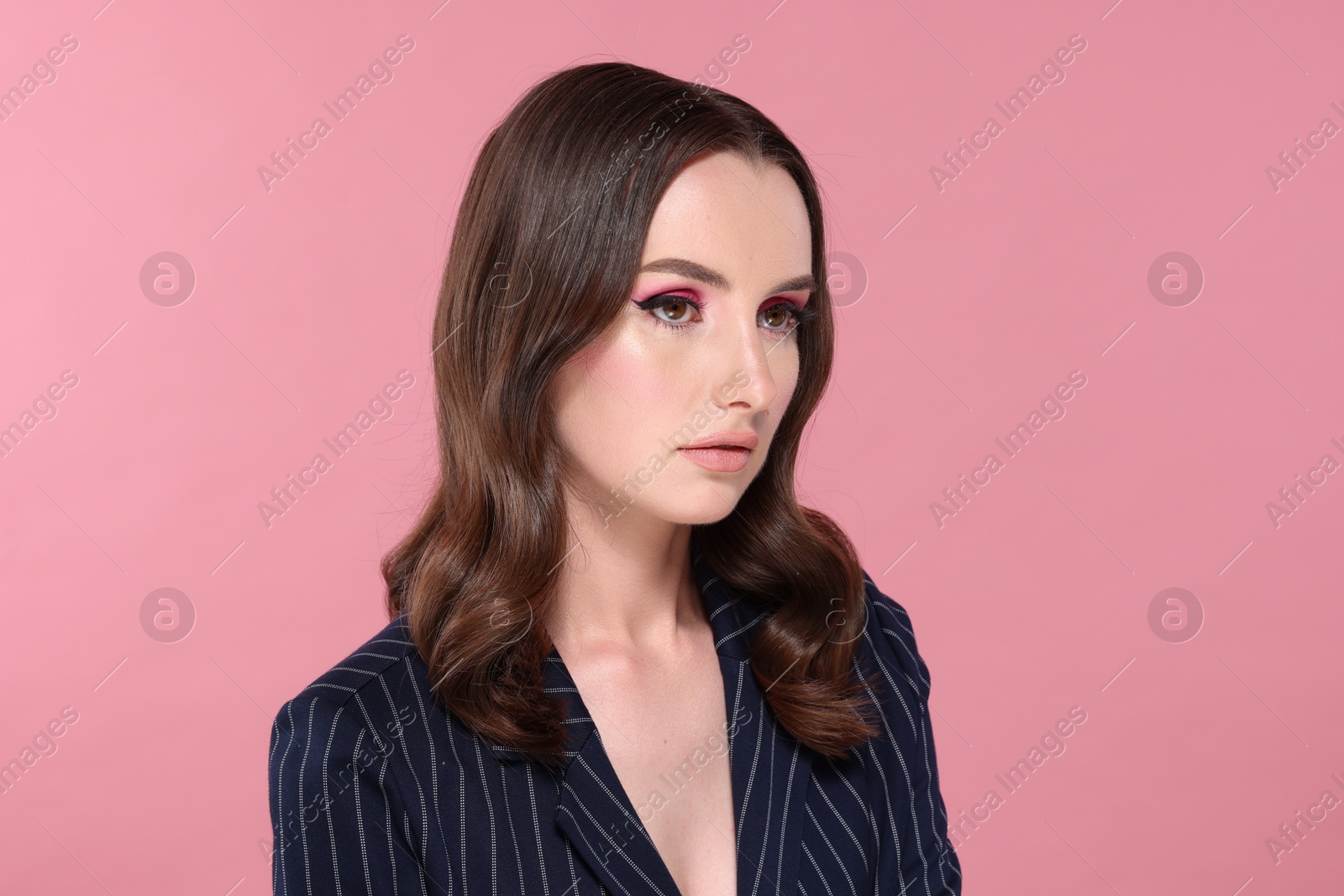 Photo of Portrait of beautiful young woman with stylish makeup and gorgeous hair on pink background