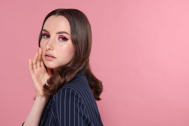 Photo of Portrait of beautiful young woman with stylish makeup and gorgeous hair on pink background. Space for text