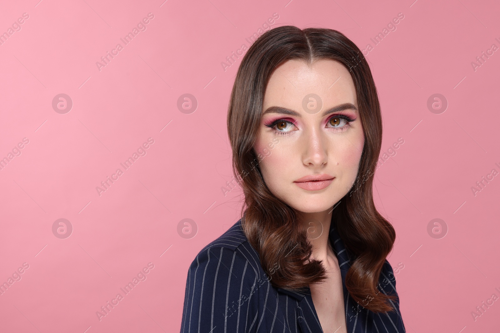 Photo of Portrait of beautiful young woman with stylish makeup and gorgeous hair on pink background. Space for text