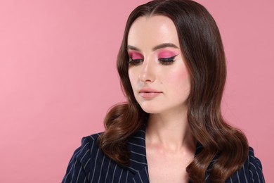 Photo of Portrait of beautiful young woman with stylish makeup and gorgeous hair on pink background. Space for text