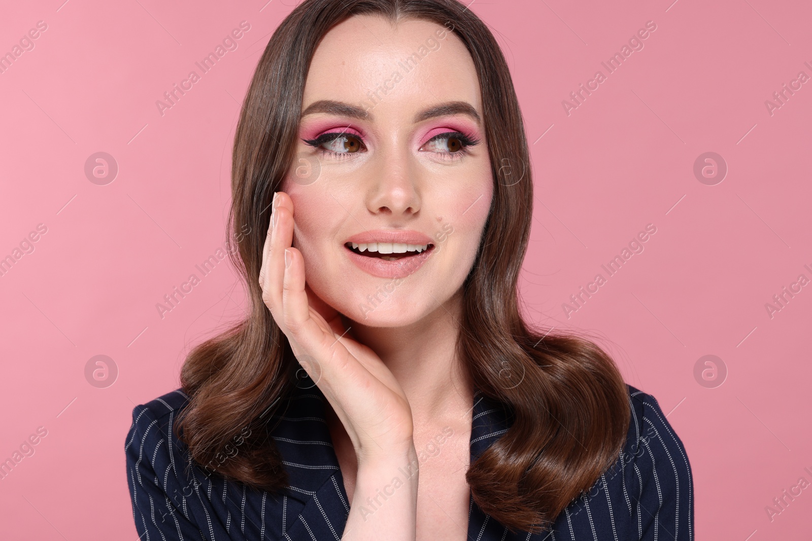 Photo of Portrait of beautiful young woman with stylish makeup and gorgeous hair on pink background