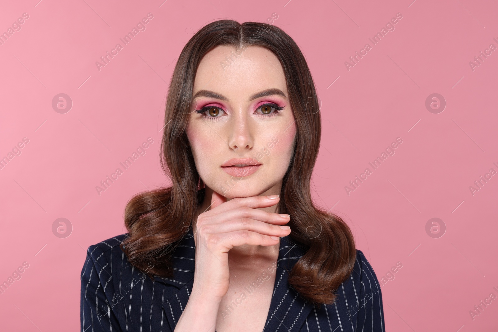 Photo of Portrait of beautiful young woman with stylish makeup and gorgeous hair on pink background