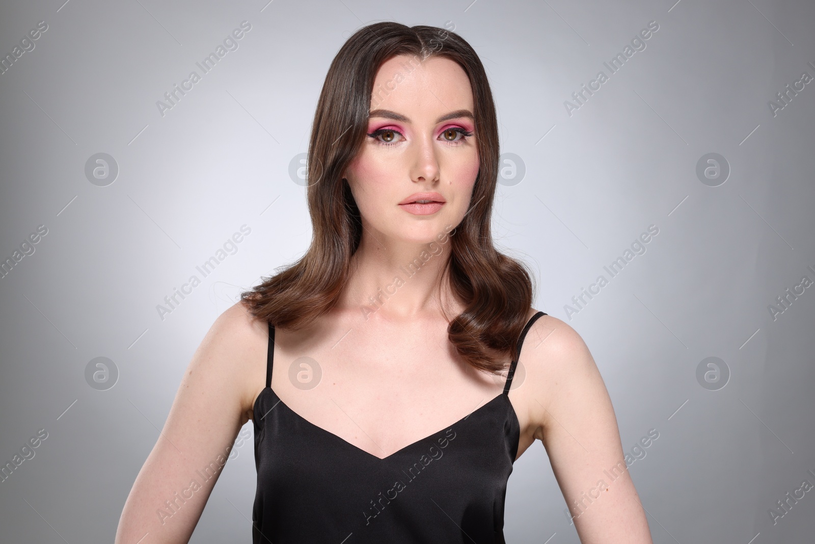 Photo of Portrait of beautiful young woman with stylish makeup and gorgeous hair on light grey background