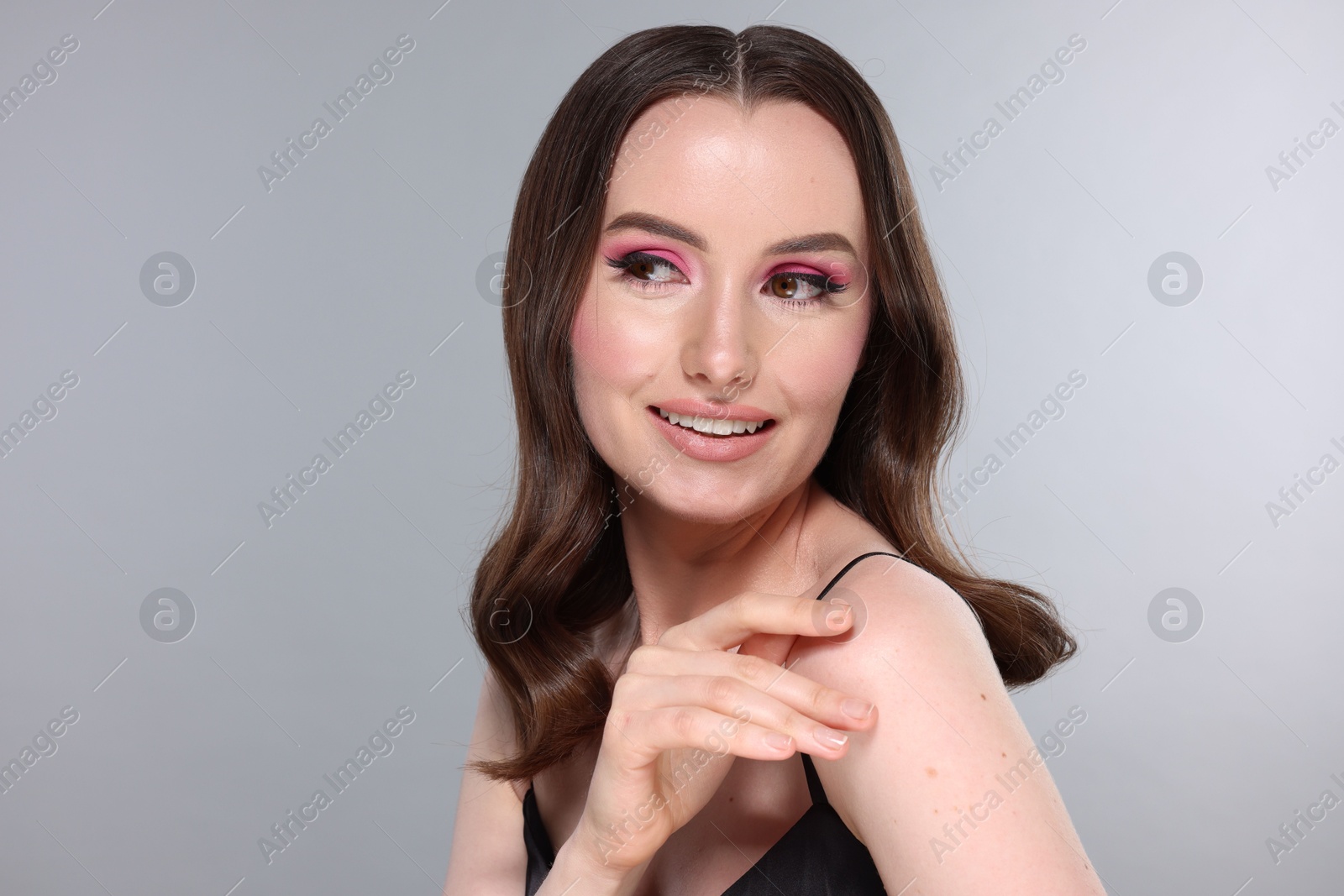 Photo of Portrait of beautiful young woman with stylish makeup and gorgeous hair on light grey background. Space for text