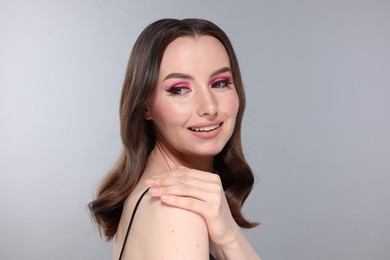 Photo of Portrait of beautiful young woman with stylish makeup and gorgeous hair on light grey background