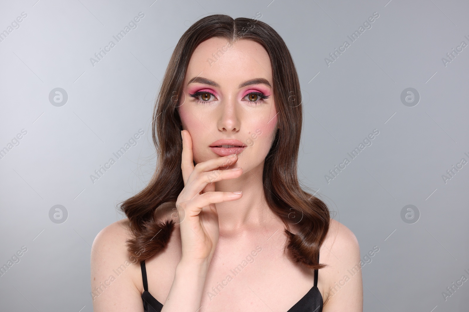 Photo of Portrait of beautiful young woman with stylish makeup and gorgeous hair on light grey background