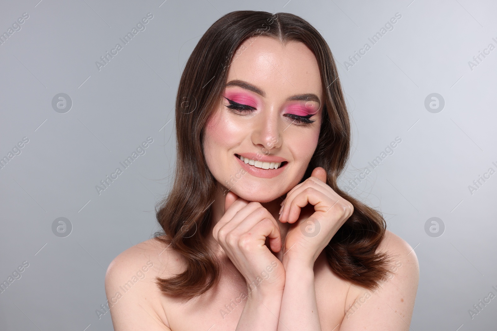 Photo of Portrait of beautiful young woman with stylish makeup and gorgeous hair on light grey background