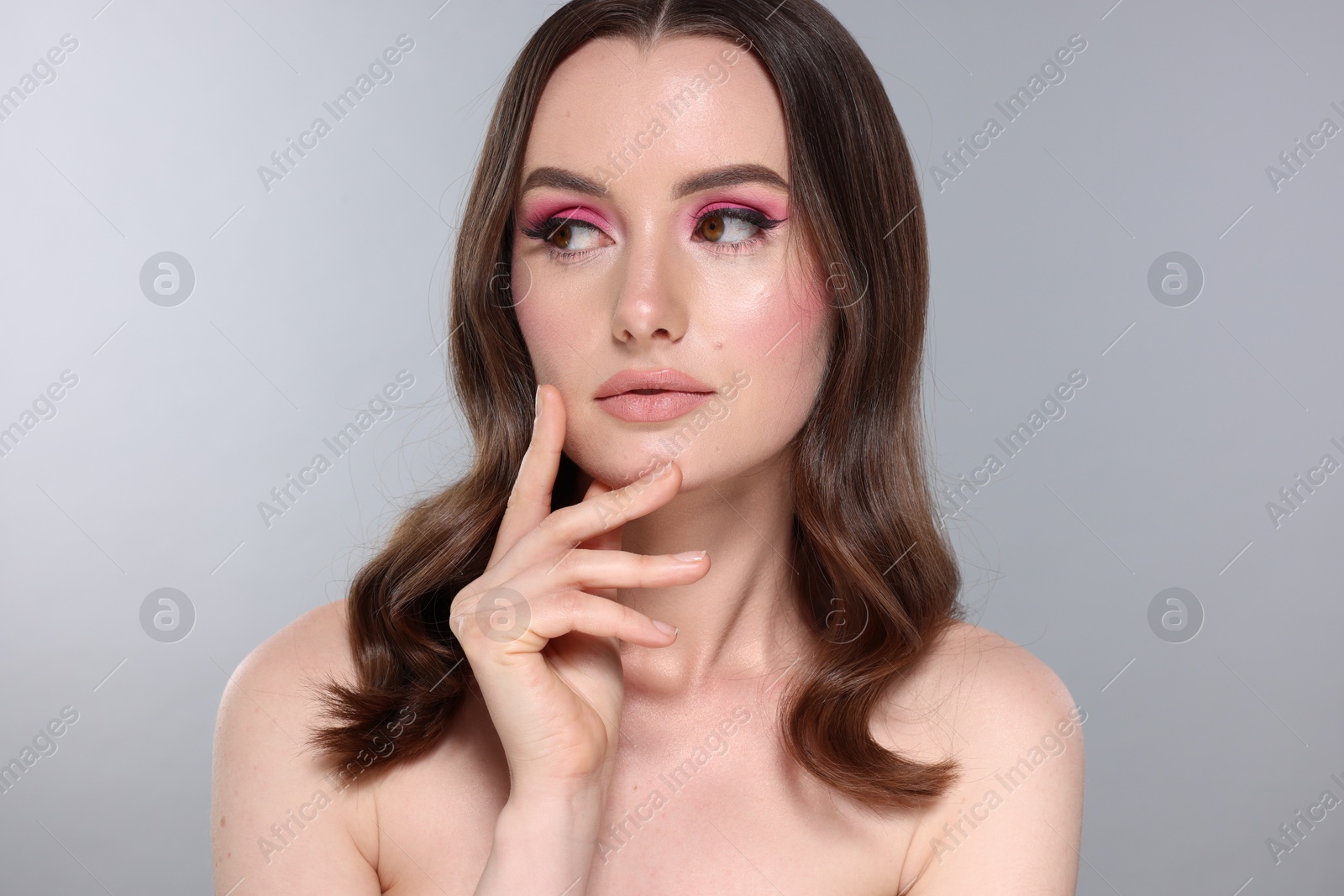 Photo of Portrait of beautiful young woman with stylish makeup and gorgeous hair on light grey background