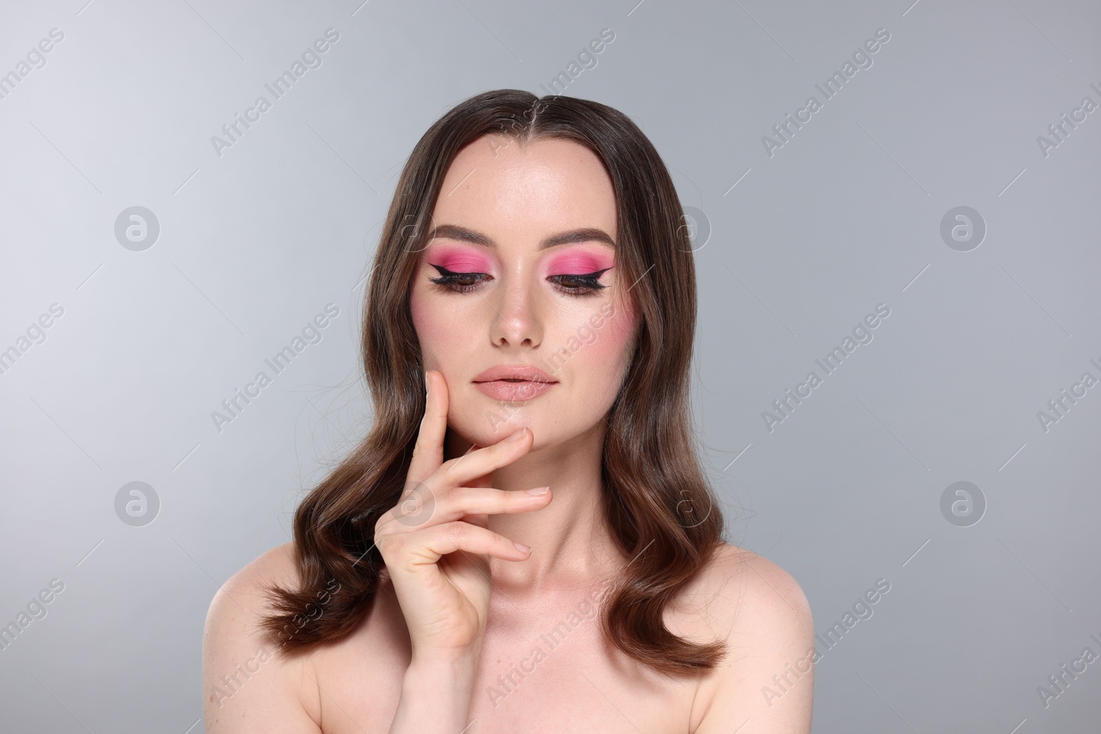 Photo of Portrait of beautiful young woman with stylish makeup and gorgeous hair on light grey background