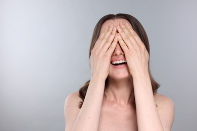 Photo of Young woman with gorgeous hair covering her face on light grey background,. Space for text