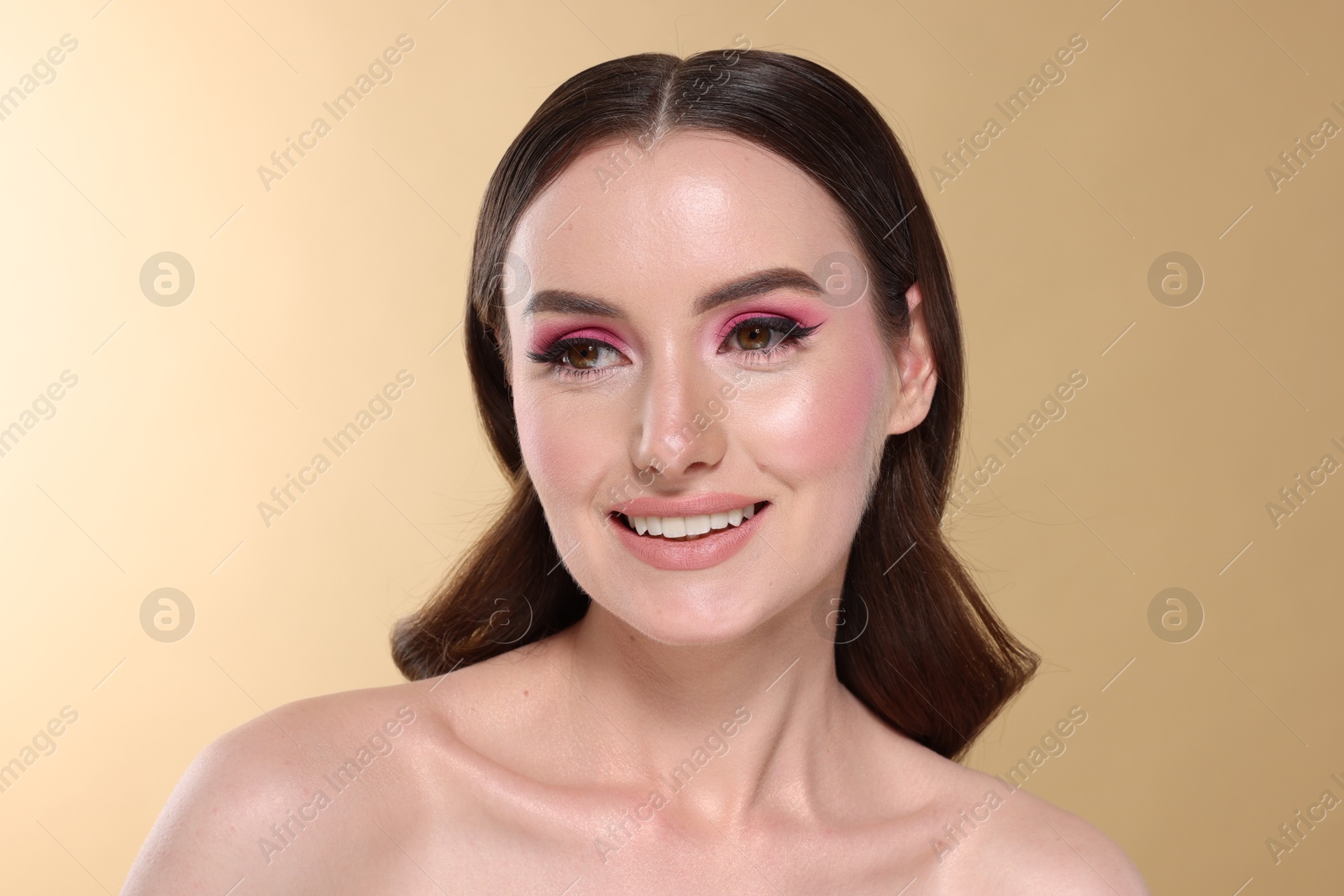 Photo of Portrait of beautiful young woman with stylish makeup and gorgeous hair on beige background