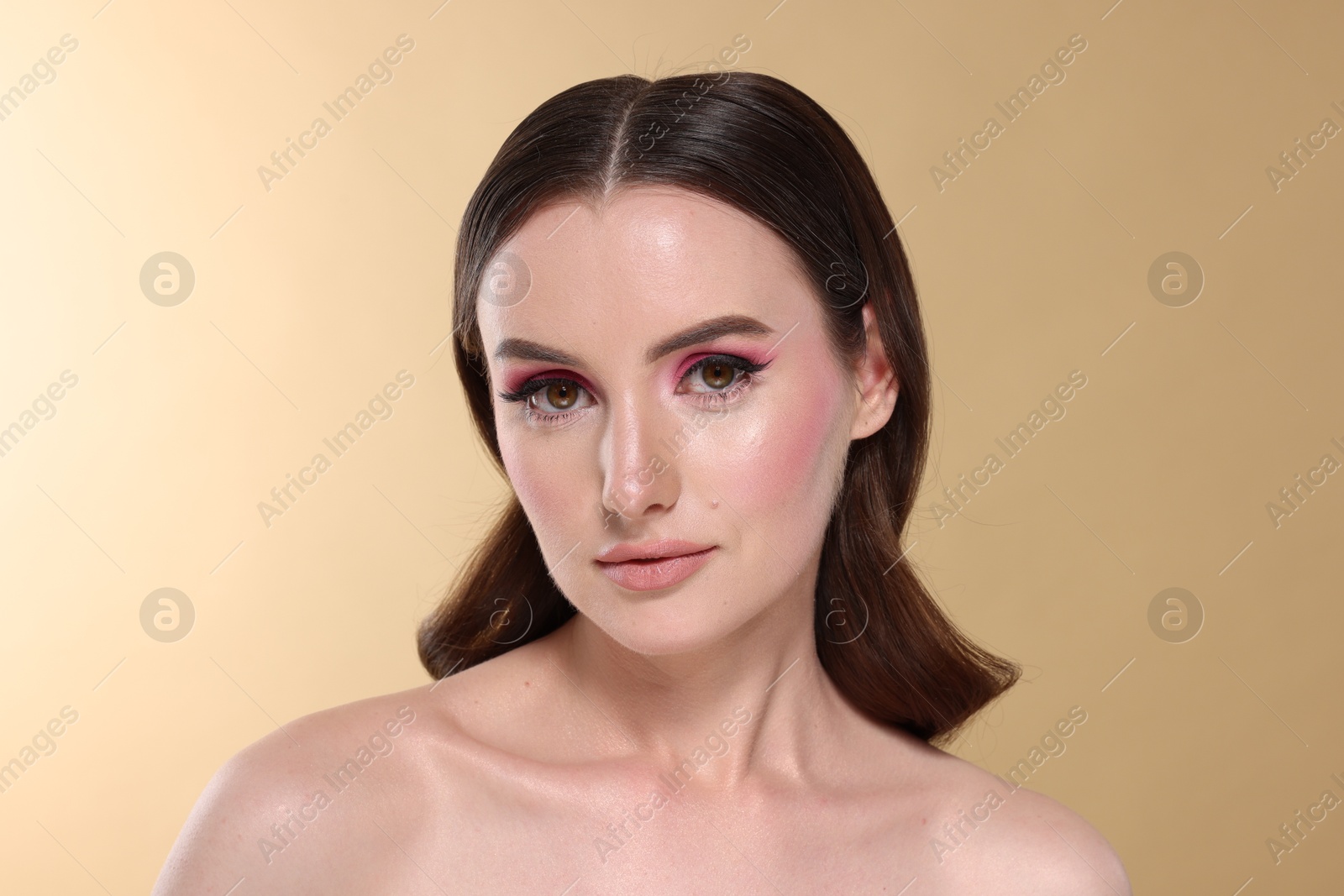 Photo of Portrait of beautiful young woman with stylish makeup and gorgeous hair on beige background