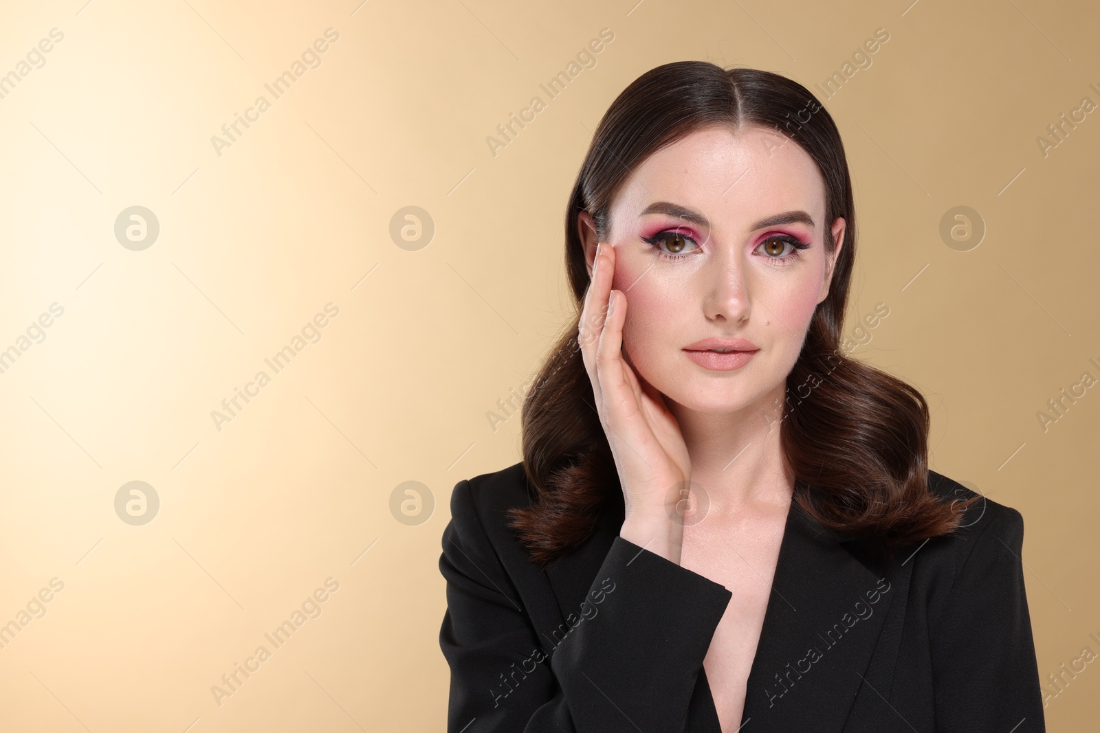 Photo of Portrait of beautiful young woman with stylish makeup and gorgeous hair on beige background. Space for text