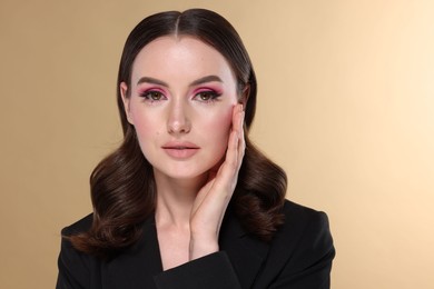 Photo of Portrait of beautiful young woman with stylish makeup and gorgeous hair on beige background