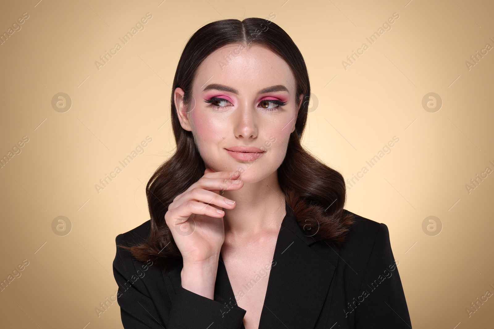 Photo of Portrait of beautiful young woman with stylish makeup and gorgeous hair on beige background