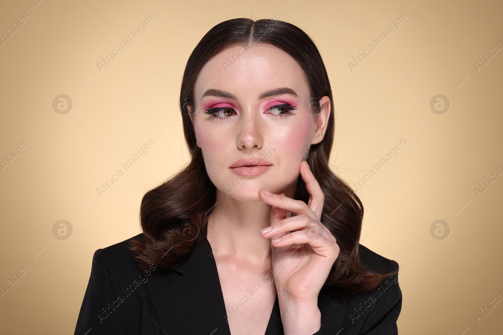 Photo of Portrait of beautiful young woman with stylish makeup and gorgeous hair on beige background