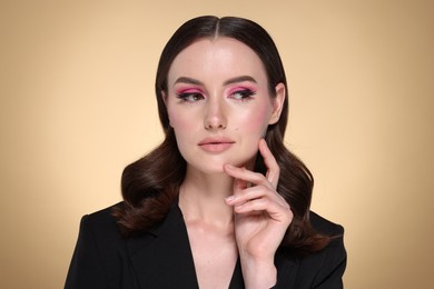 Photo of Portrait of beautiful young woman with stylish makeup and gorgeous hair on beige background