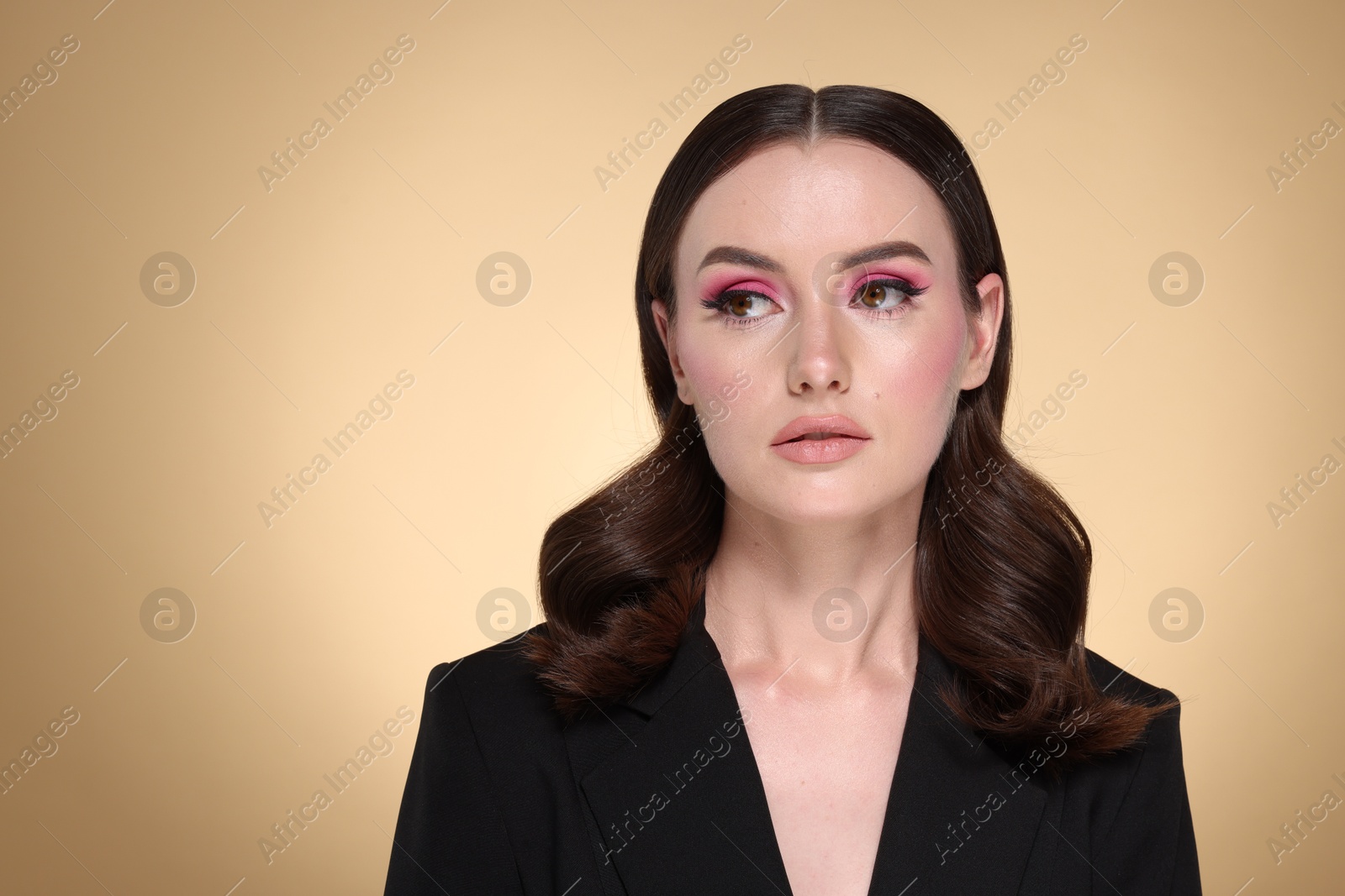 Photo of Portrait of beautiful young woman with stylish makeup and gorgeous hair on beige background. Space for text