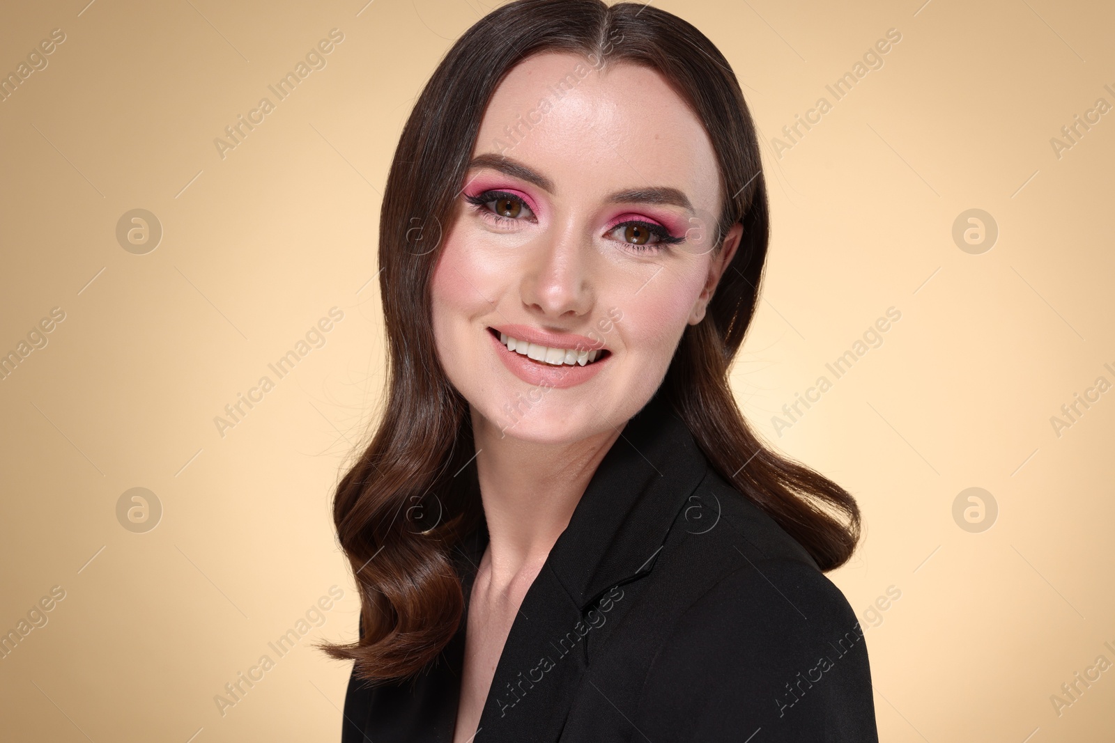 Photo of Portrait of beautiful young woman with stylish makeup and gorgeous hair on beige background