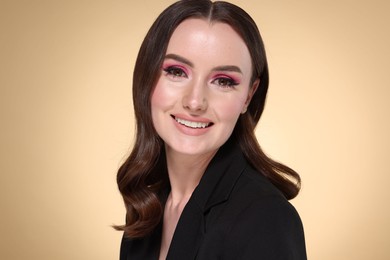 Photo of Portrait of beautiful young woman with stylish makeup and gorgeous hair on beige background