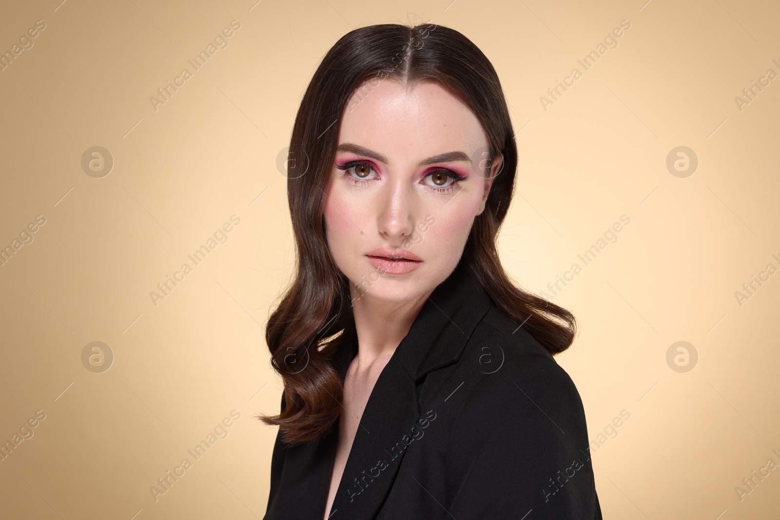 Photo of Portrait of beautiful young woman with stylish makeup and gorgeous hair on beige background