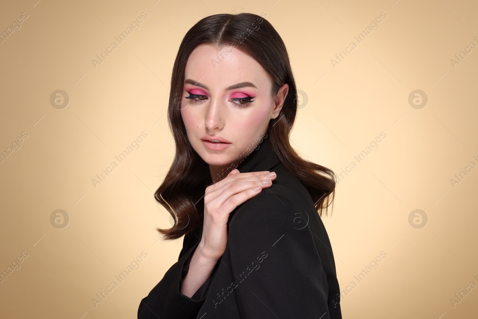 Photo of Portrait of beautiful young woman with stylish makeup and gorgeous hair on beige background