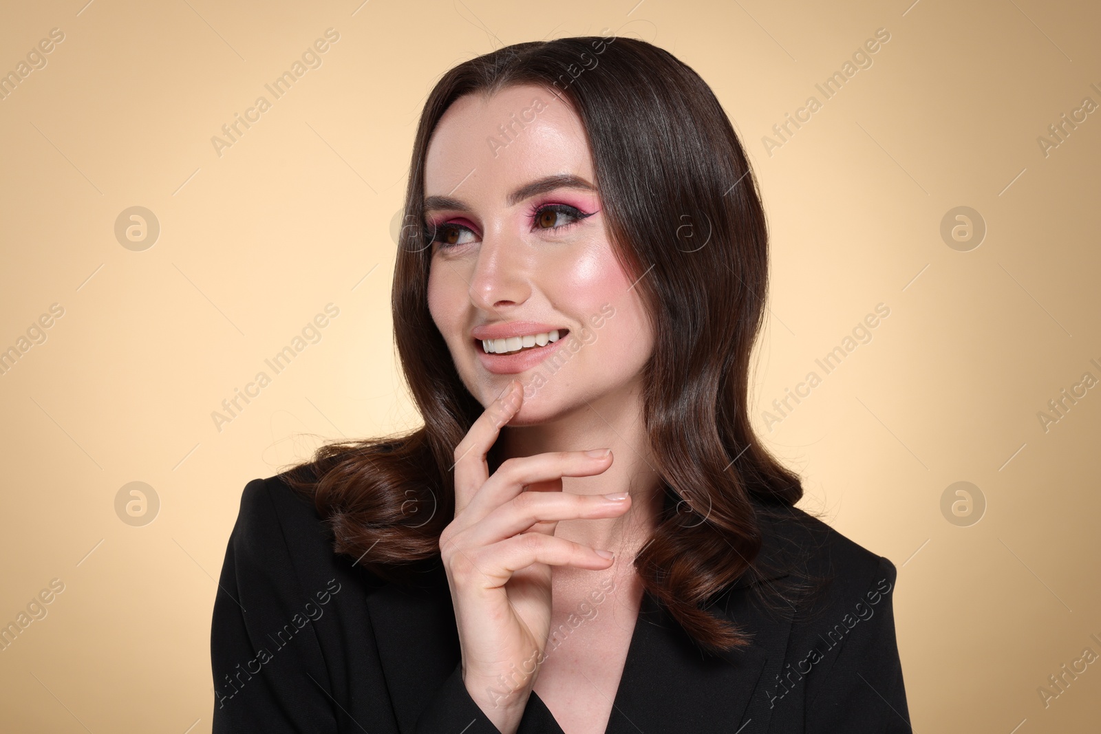 Photo of Portrait of beautiful young woman with stylish makeup and gorgeous hair on beige background