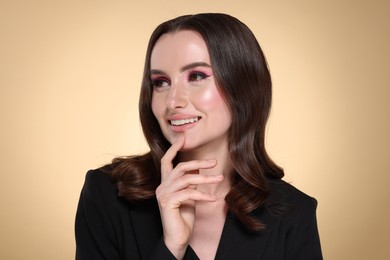 Photo of Portrait of beautiful young woman with stylish makeup and gorgeous hair on beige background