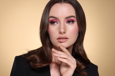 Photo of Portrait of beautiful young woman with stylish makeup and gorgeous hair on beige background