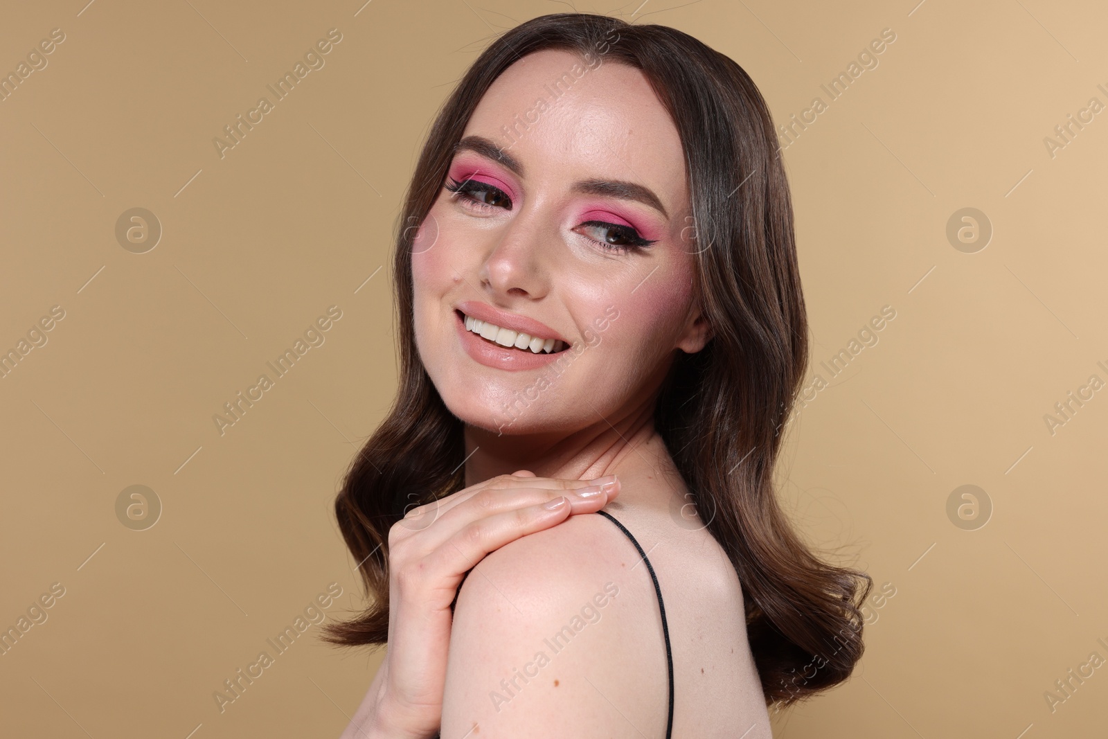 Photo of Portrait of beautiful young woman with stylish makeup and gorgeous hair on beige background