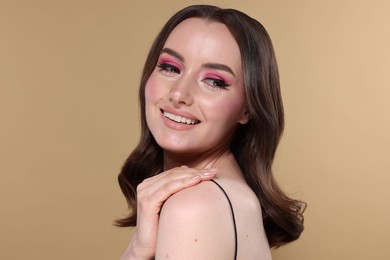 Photo of Portrait of beautiful young woman with stylish makeup and gorgeous hair on beige background