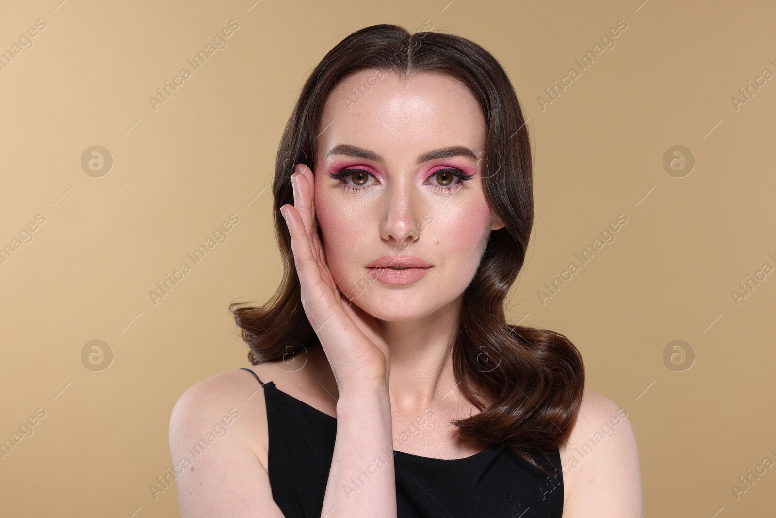 Photo of Portrait of beautiful young woman with stylish makeup and gorgeous hair on beige background