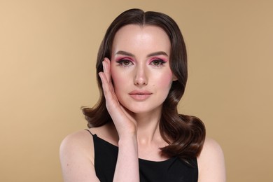 Photo of Portrait of beautiful young woman with stylish makeup and gorgeous hair on beige background