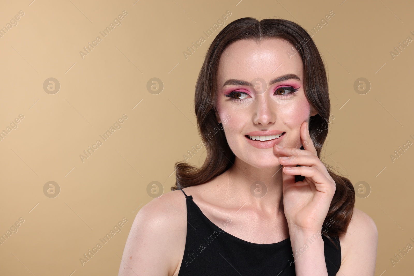 Photo of Portrait of beautiful young woman with stylish makeup and gorgeous hair on beige background. Space for text