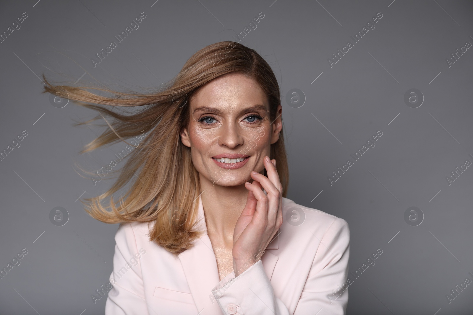 Photo of Portrait of beautiful happy woman with straight blonde hair on grey background