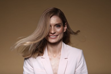 Photo of Portrait of beautiful happy woman with straight blonde hair on light brown background